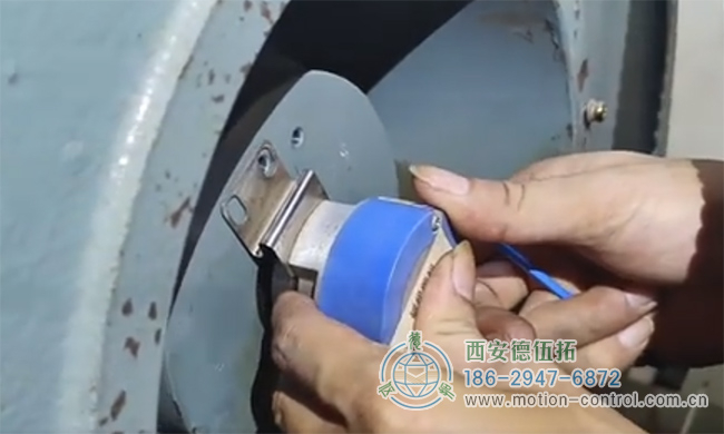 图为工作人员正在对发生飞车现象的电梯编码器进行拆御的照片