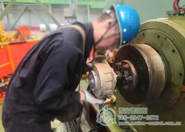 图为工人为彩涂酸轧轧机回装编码器的照片